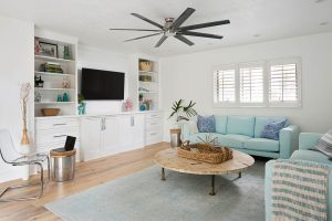 Interior of newly remodeled home featuring wood flooring, beach-style couches, and white entertainment center.