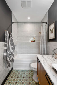 Newly remodeled bathroom with patterned flooring, low-maintenance bathtub, and marble countertop.
