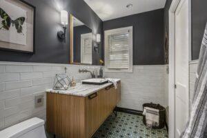 Newly remodeled bathroom with wood cabinets, subway-style tiled walls, and walk-in shower.