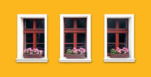 White wooden windows with flower boxes in the side of a bright yellow house